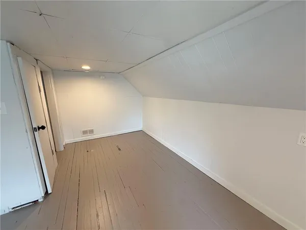 an empty room with wooden floor and entrance