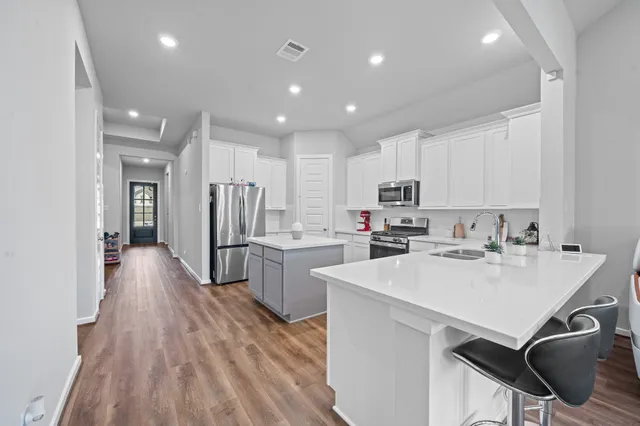 a kitchen with stainless steel appliances white cabinets sink and stove top oven