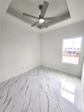 an empty room with windows and fan