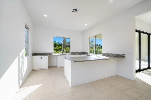 a large white kitchen with a sink and dishwasher next to a window