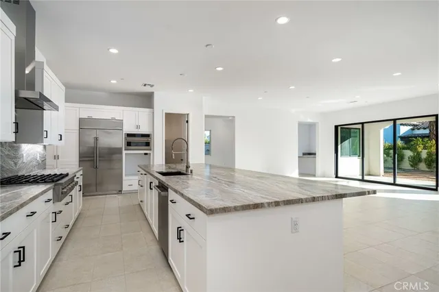 a large kitchen with stainless steel appliances granite countertop a stove a sink a refrigerator and white cabinets