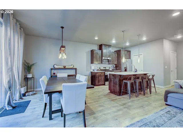 a open kitchen with stainless steel appliances kitchen island granite countertop a table chairs and a refrigerator