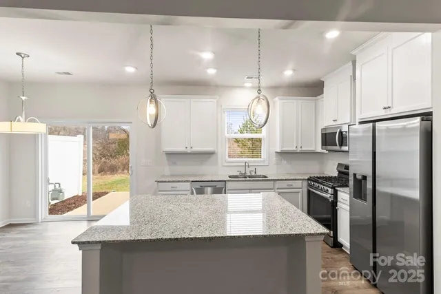 a kitchen with stainless steel appliances granite countertop a sink stove and cabinets