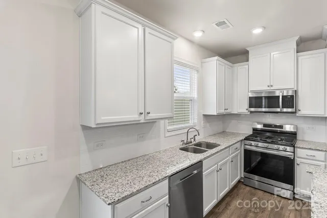 a kitchen with stainless steel appliances granite countertop a sink stove and refrigerator
