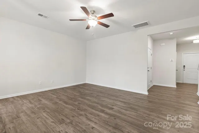 an empty room with wooden floor ceiling fan and window