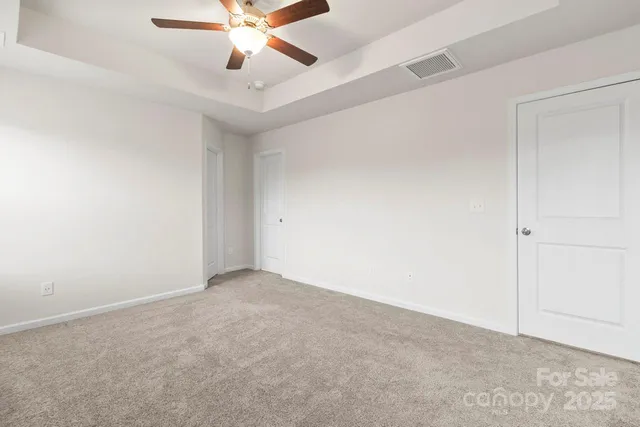 an empty room with a ceiling fan and carpet