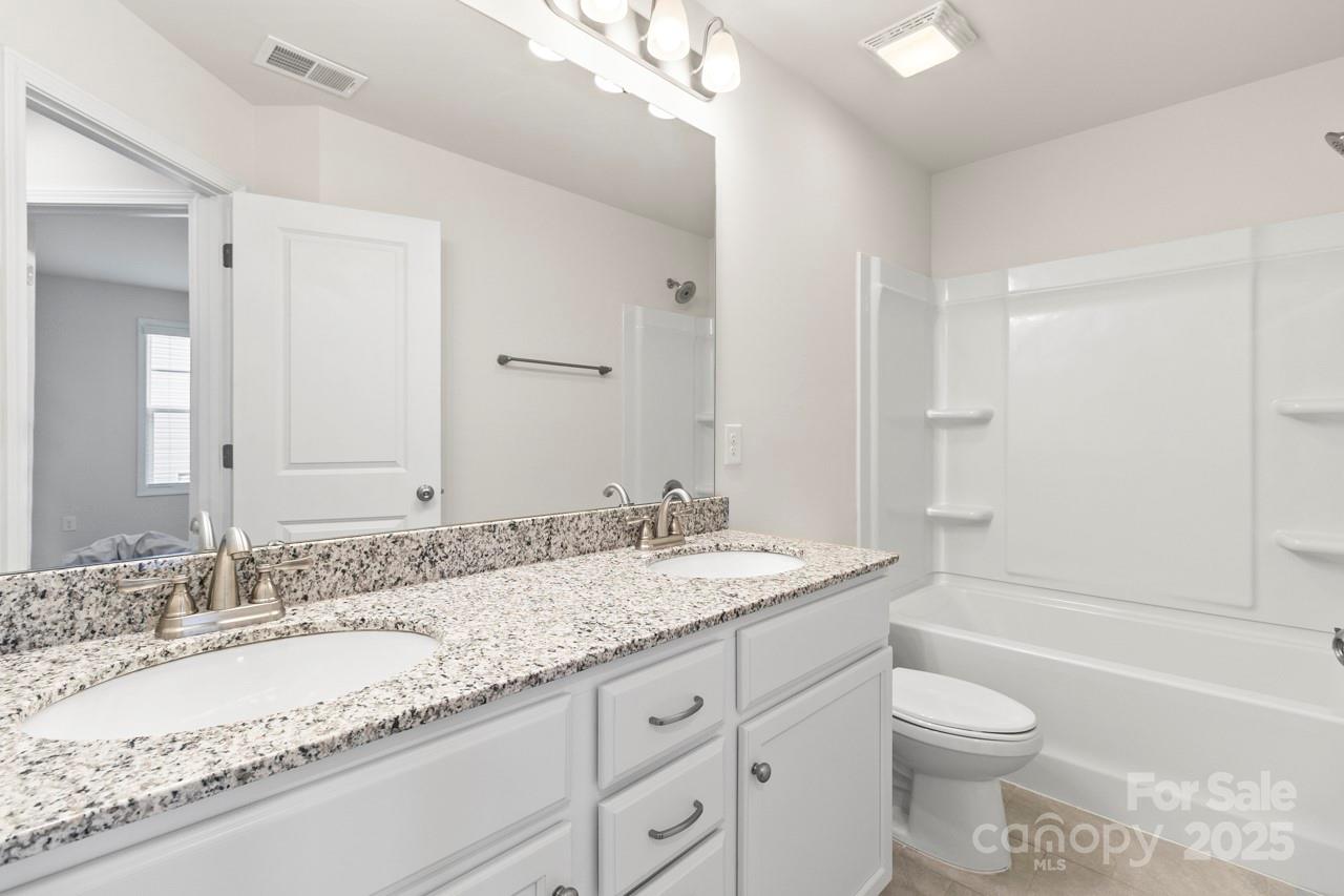 3776 Yorkshire Place Terrell, NC 28682 - Photo 41 of 47 a bathroom with a granite countertop sink toilet a large mirror a bathtub and shower