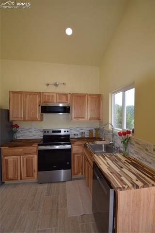 80 Spur Road Divide, CO 80814 - Photo 15 of 48 Kitchen featuring butcher block countertops, stove, backsplash, dishwashing machine, and high vaulted ceiling