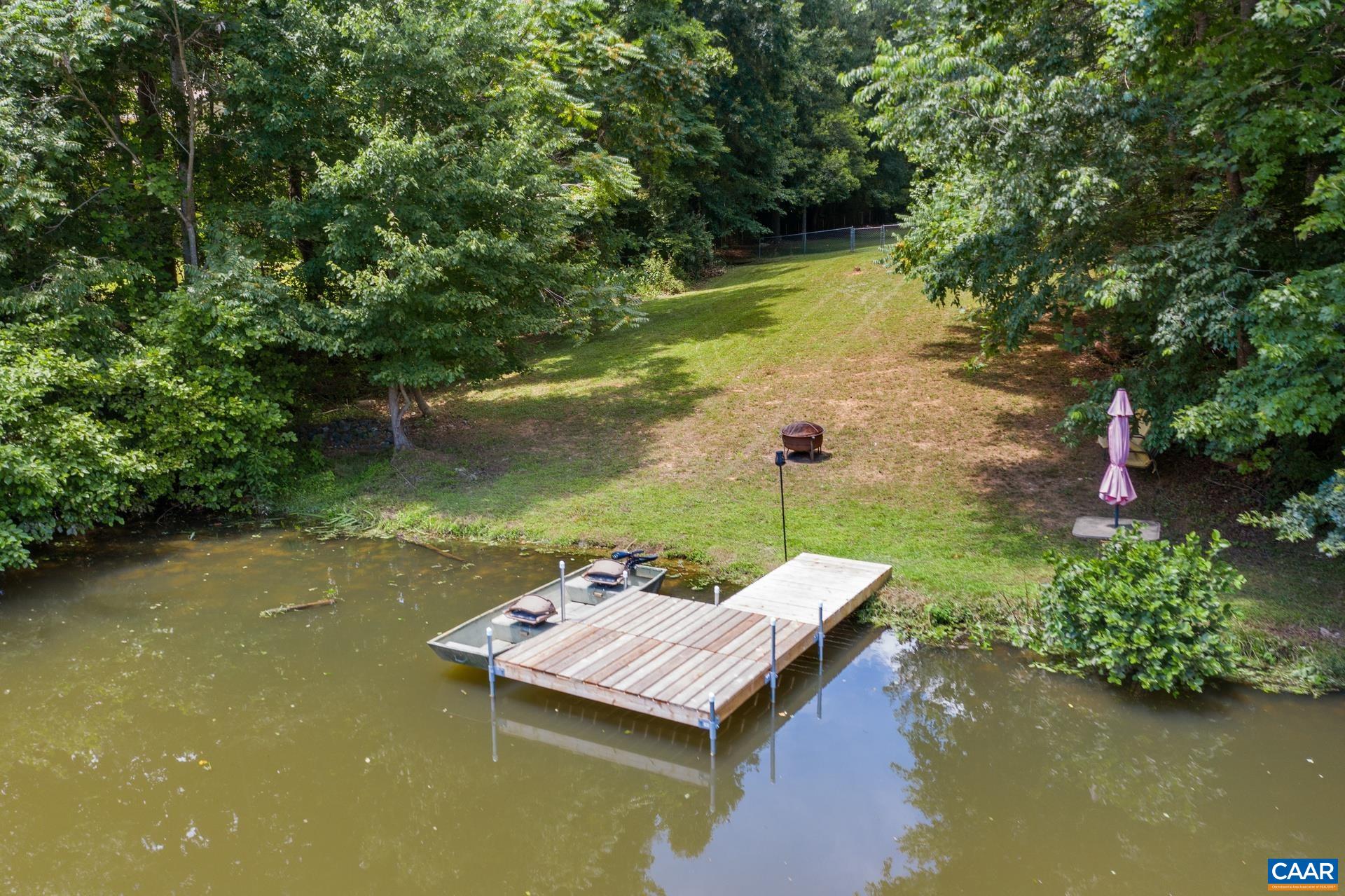 793 Geranium Road Ruckersville, VA 22968 - Photo 3 of 31 a view of a lake with lawn chairs under an umbrella