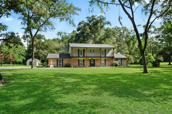 a view of a big house with a big yard and large trees
