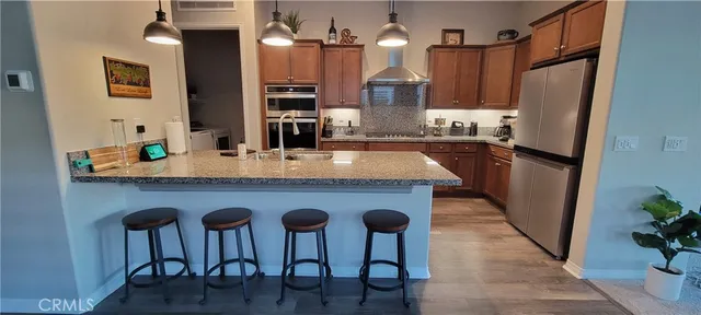 a kitchen with stainless steel appliances granite countertop a refrigerator a stove and a wooden floors