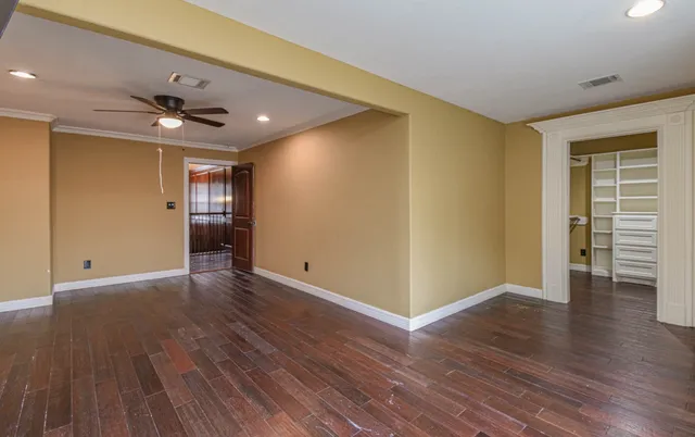 a view of an empty room with a window and wooden floor