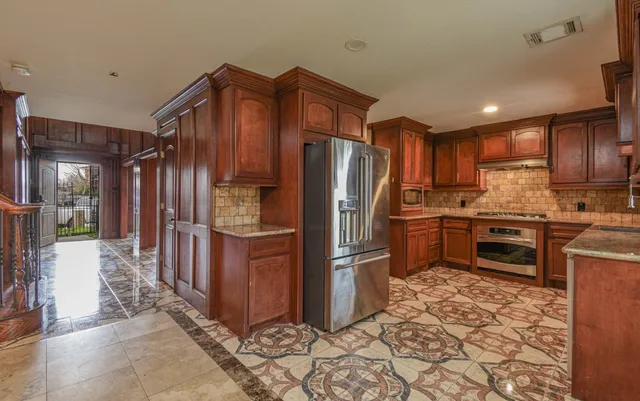 a kitchen with stainless steel appliances granite countertop a refrigerator and a stove top oven