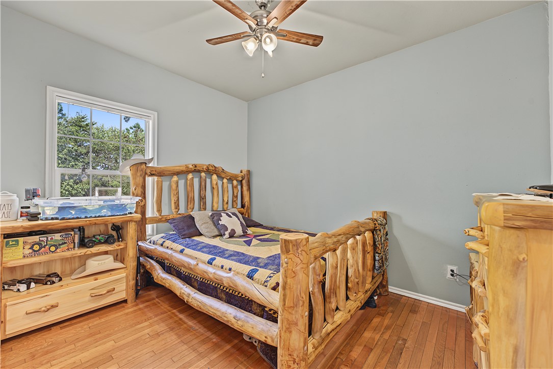 15282 Burgin Valley Road Gravette, AR 72736 - Photo 16 of 53 Hardwood flooring, light blue wall paint, and a window with white trim