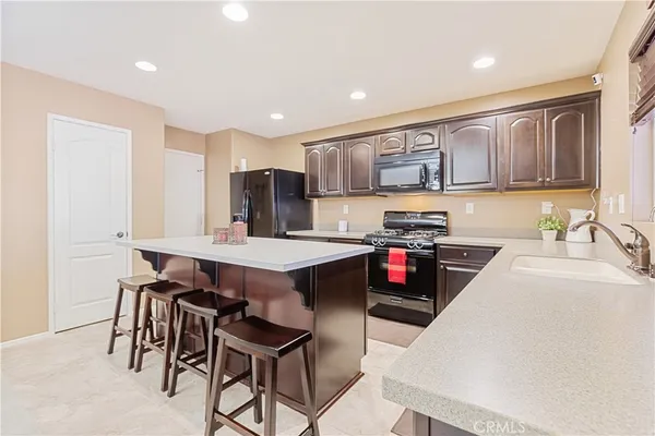 a kitchen with stainless steel appliances kitchen island granite countertop a stove a sink a refrigerator and a refrigerator