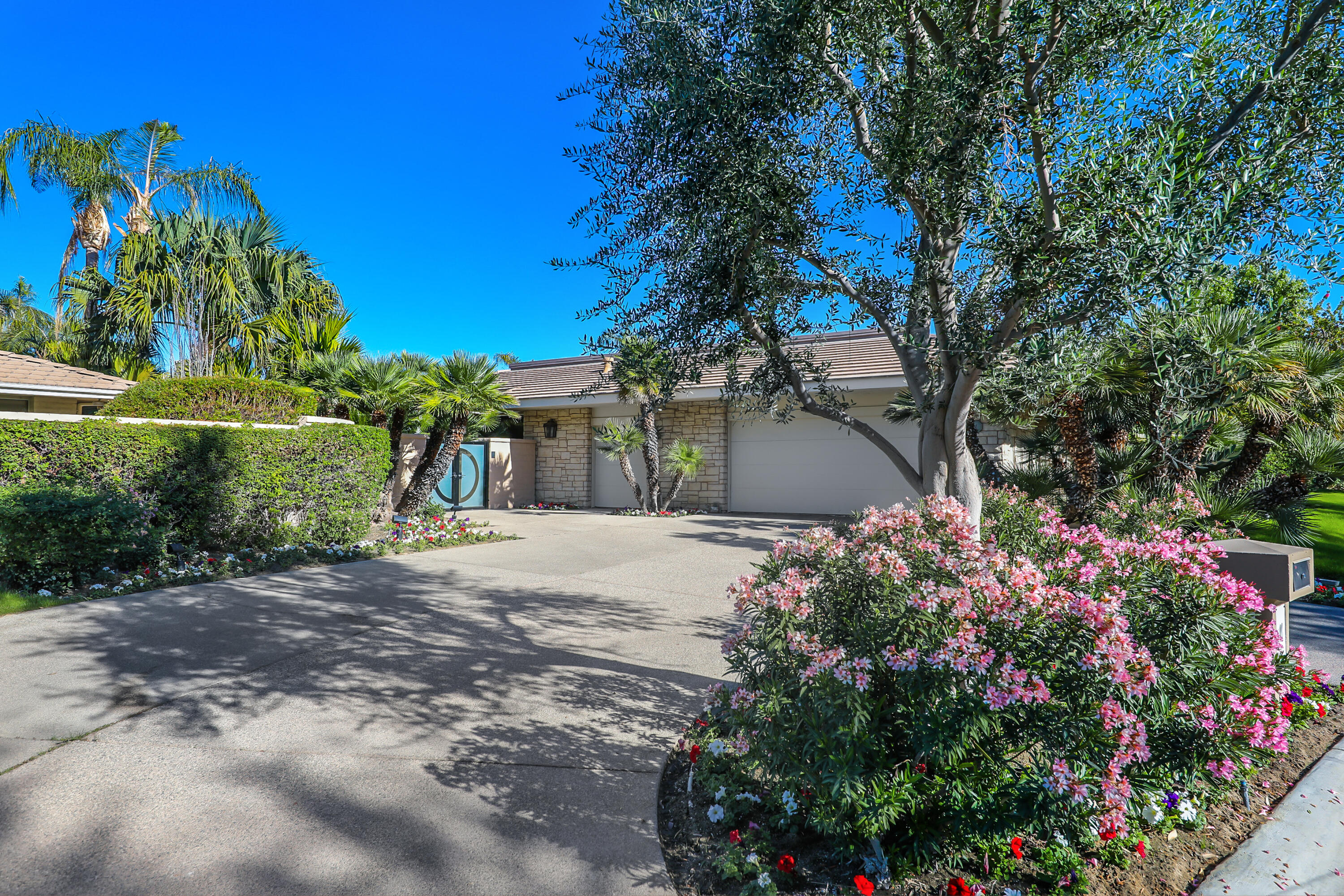 44 Fincher Way Rancho Mirage, CA 92270 - Photo 2 of 56 a front view of a house with a yard and fountain in middle of the road