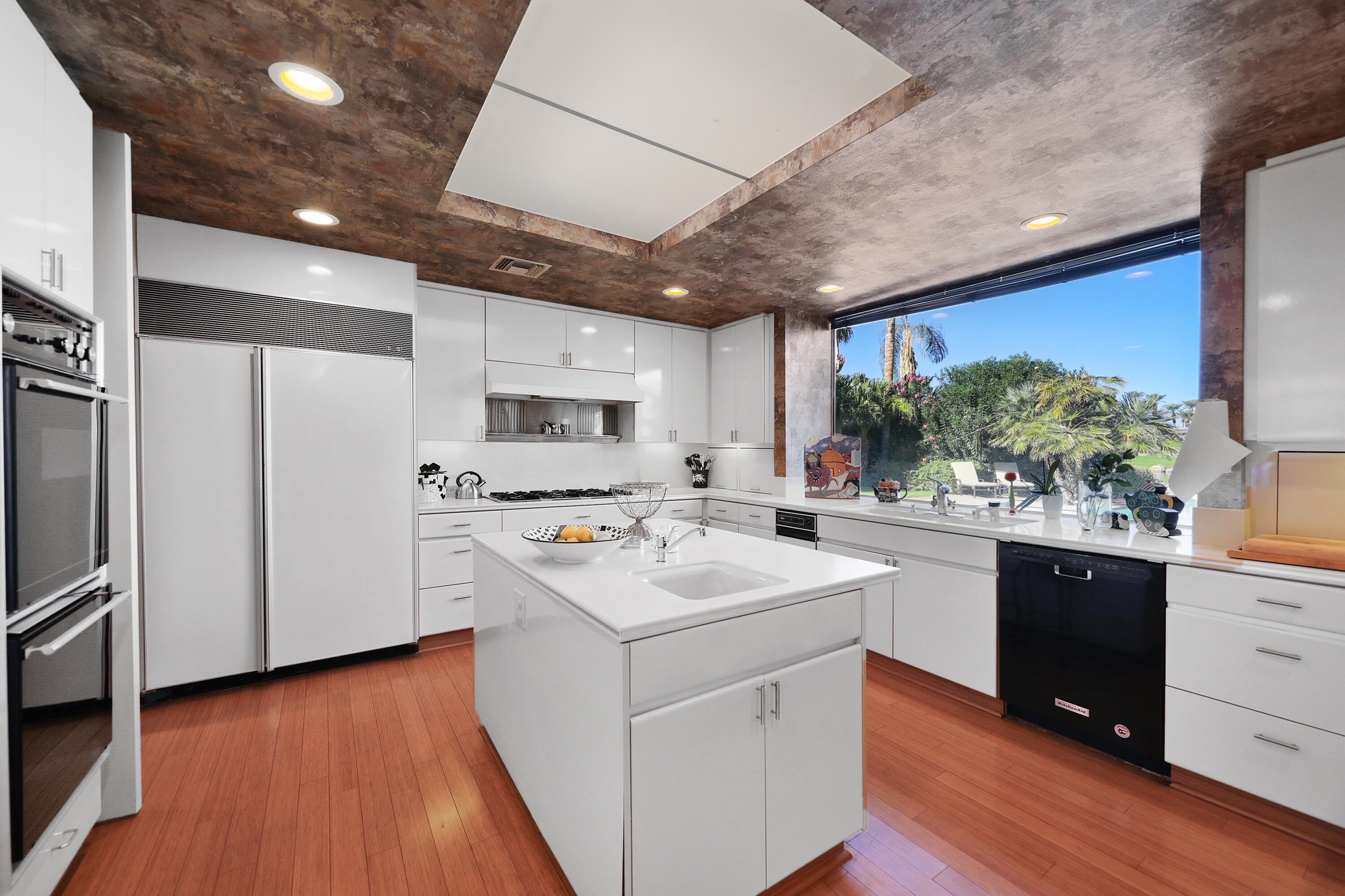 44 Fincher Way Rancho Mirage, CA 92270 - Photo 20 of 56 a kitchen with stainless steel appliances kitchen island granite countertop a sink a stove a refrigerator cabinets and wooden floor