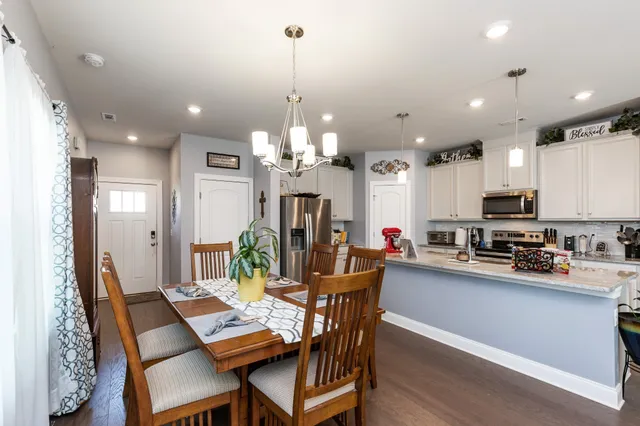 a view of a dining room and livingroom with furniture wooden floor a chandelier