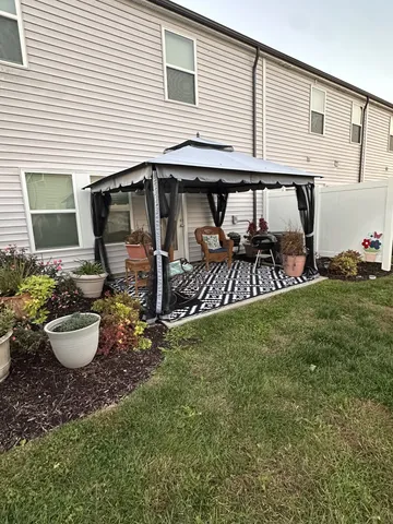 a view of a chair and table in backyard of the house