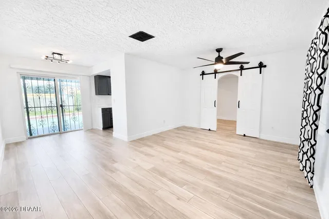 a view of empty room with wooden floor and fan
