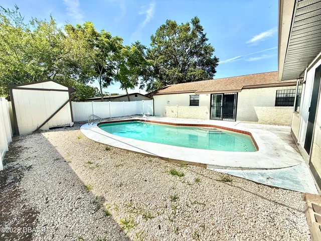 a view of a backyard with a large tree and wooden fence