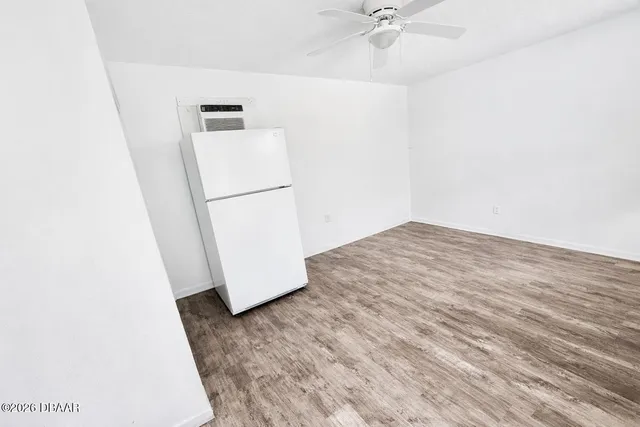 a view of a room with wooden floor and a ceiling fan