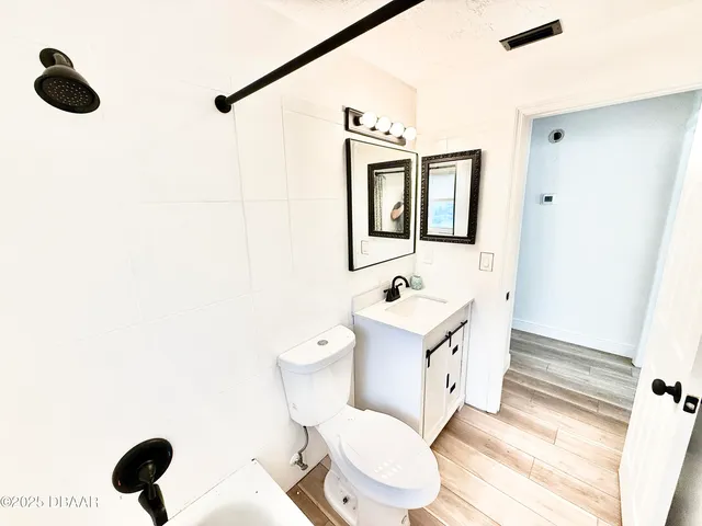 a bathroom with a toilet sink a mirror a vanity and shower