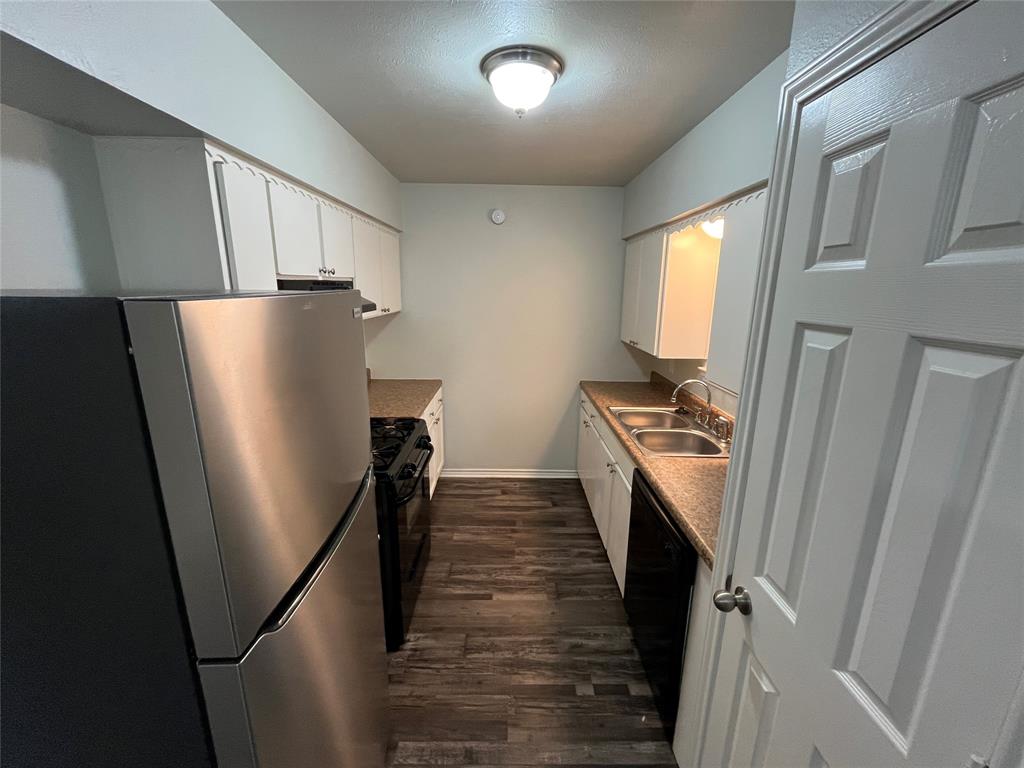 1841 South Perry Road Carrollton, TX 75006 - Photo 8 of 25 Kitchen featuring black appliances, a textured ceiling, dark wood finished floors, white cabinets, and dark countertops