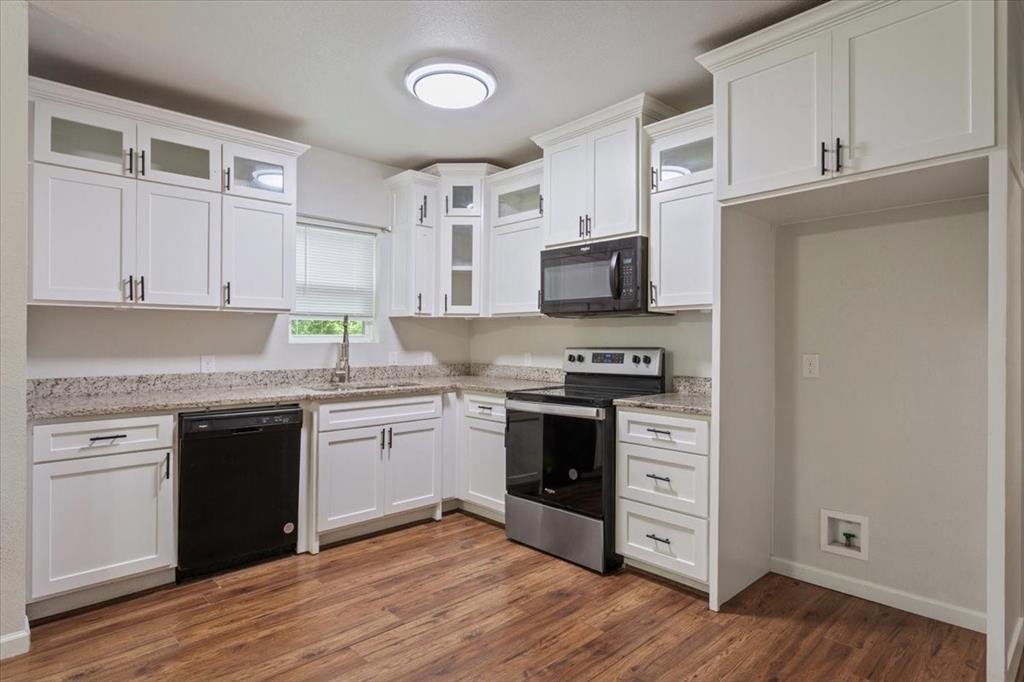 3109 North 20th Street Waco, TX 76708 - Photo 8 of 24 Kitchen featuring wood-finish flooring, white cabinetry with black hardware, stone-finish countertops, and built-in appliances