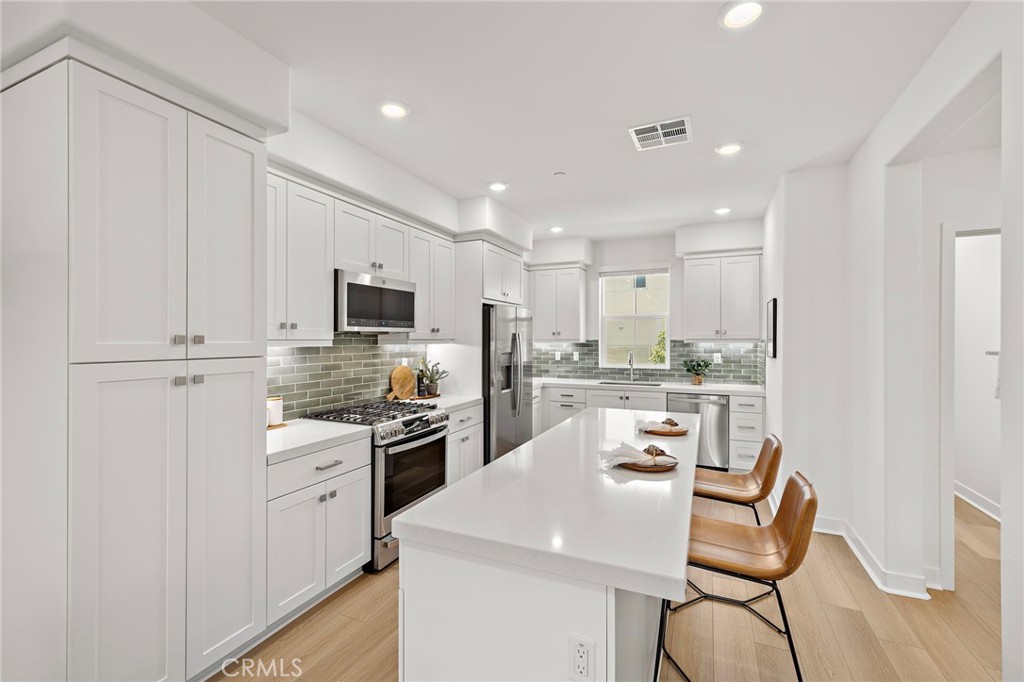 61 Wheelbarrow Road Rancho Mission Viejo, CA 92694 - Photo 4 of 74 a kitchen with white cabinets and stainless steel appliances