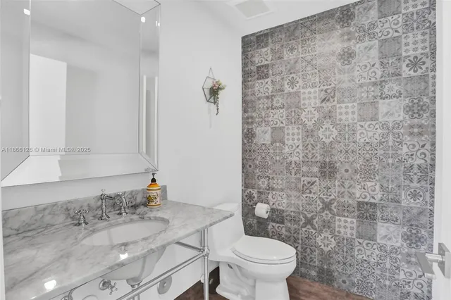 a bathroom with a granite countertop toilet and a sink