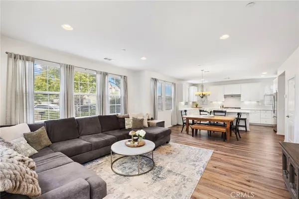 a living room with furniture and a dining table with wooden floor