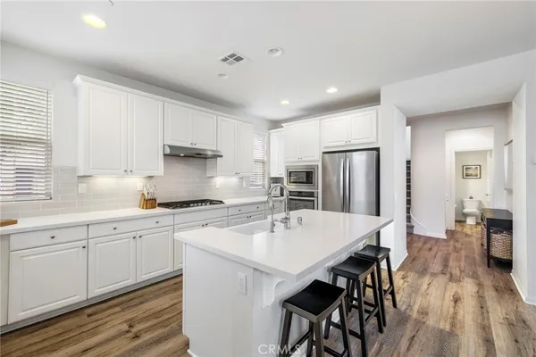 a kitchen with stainless steel appliances a table chairs refrigerator and sink