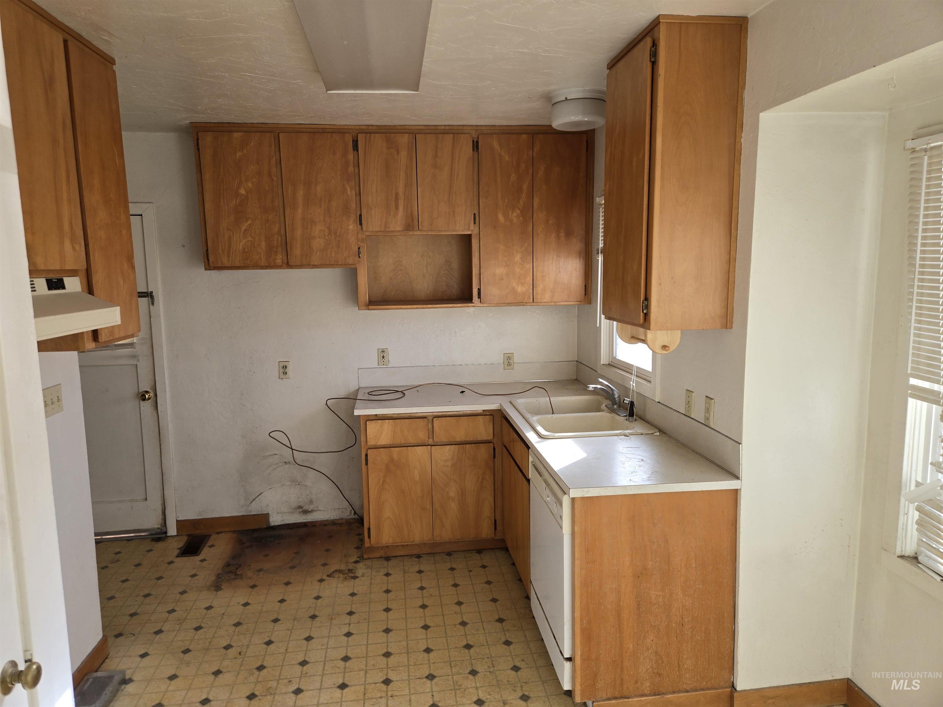 619 Thain Road Lewiston, ID 83501 - Photo 2 of 14 Kitchen featuring light flooring, light countertops, brown cabinets, dishwasher, and under cabinet range hood