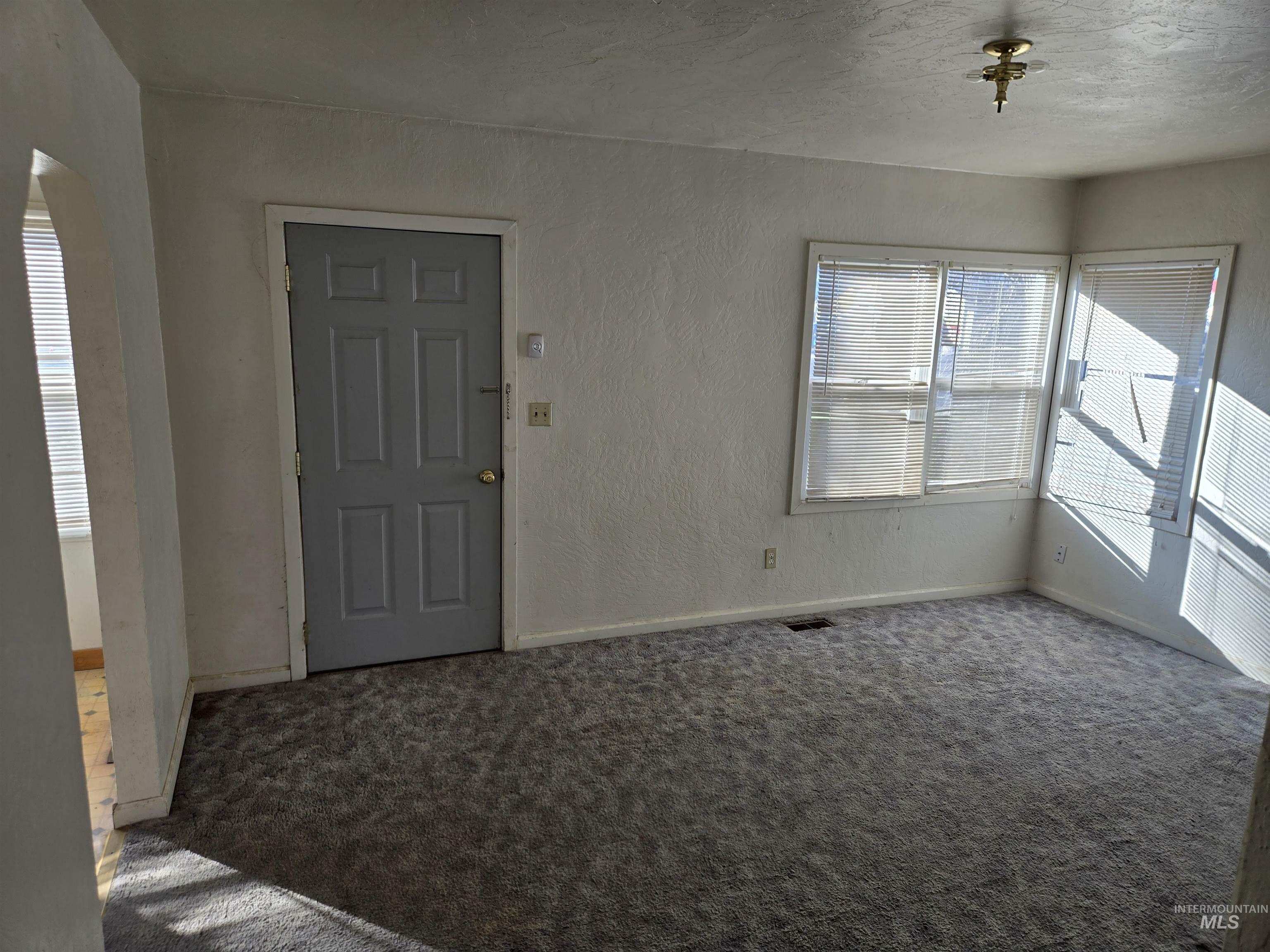 619 Thain Road Lewiston, ID 83501 - Photo 3 of 14 Carpeted empty room featuring a textured wall, a textured ceiling, and arched walkways