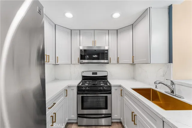 a kitchen with granite countertop white cabinets and stainless steel appliances