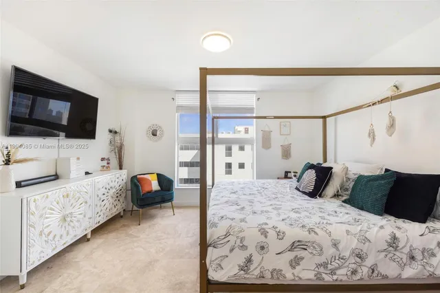a bedroom with a bed and flat tv screen on the dresser