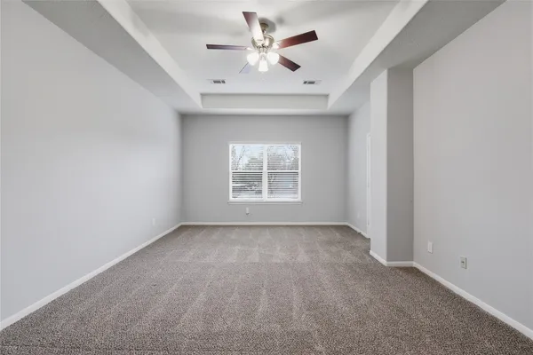 an empty room with chandelier fan and windows
