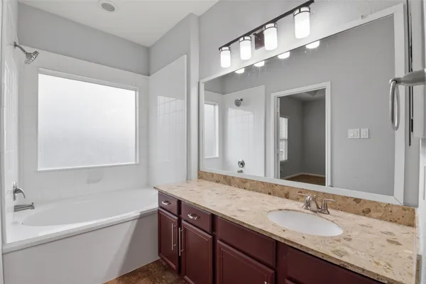 a bathroom with a granite countertop sink mirror and a bathtub