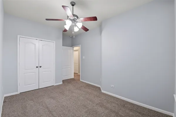 a view of an empty room and chandelier fan