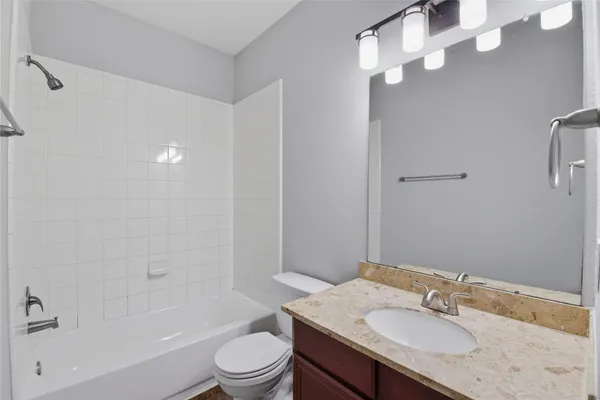 a bathroom with a granite countertop sink a toilet and shower
