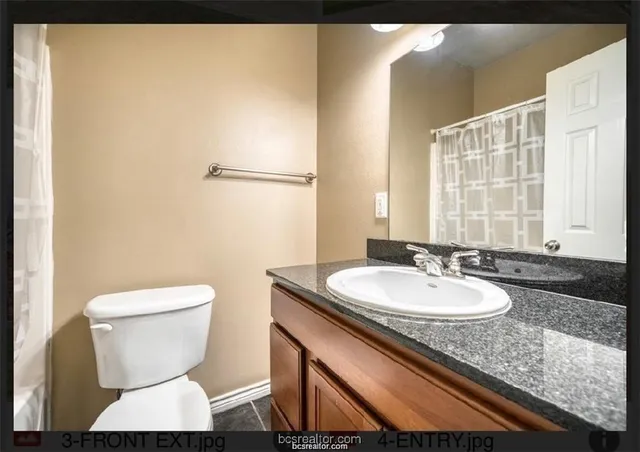 a bathroom with a granite countertop toilet a sink and a mirror