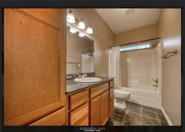 a bathroom with a granite countertop sink toilet a mirror and shower