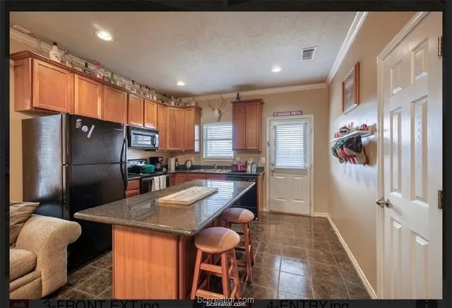 a kitchen with stainless steel appliances granite countertop a refrigerator a sink a stove and a refrigerator