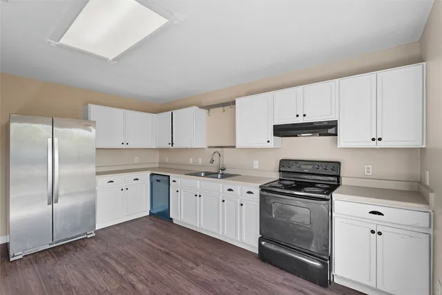 a kitchen with cabinets stainless steel appliances a sink and wooden floor