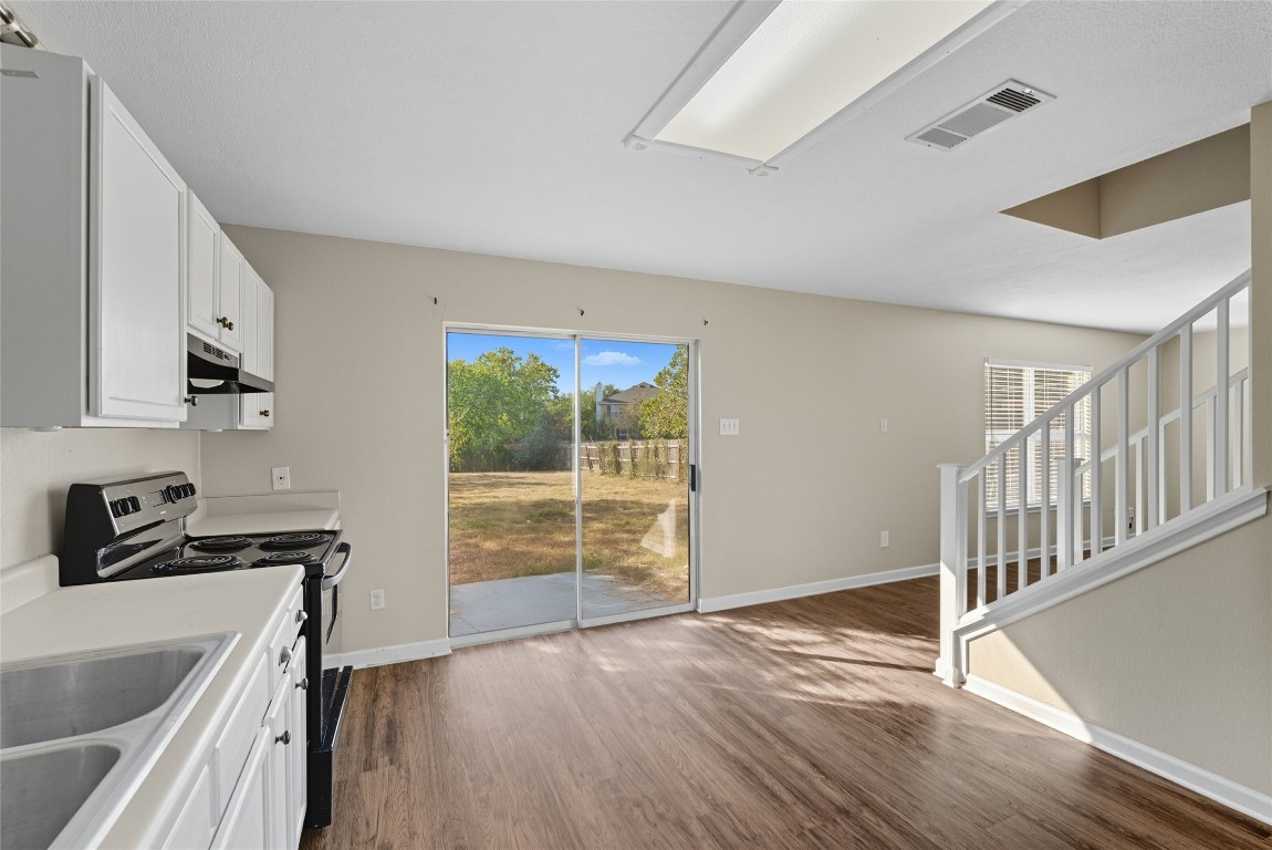 3621 Walleye Way Round Rock, TX 78665 - Photo 4 of 14 Kitchen featuring electric range oven, white cabinets, dark wood-style flooring, light countertops, and healthy amount of natural light