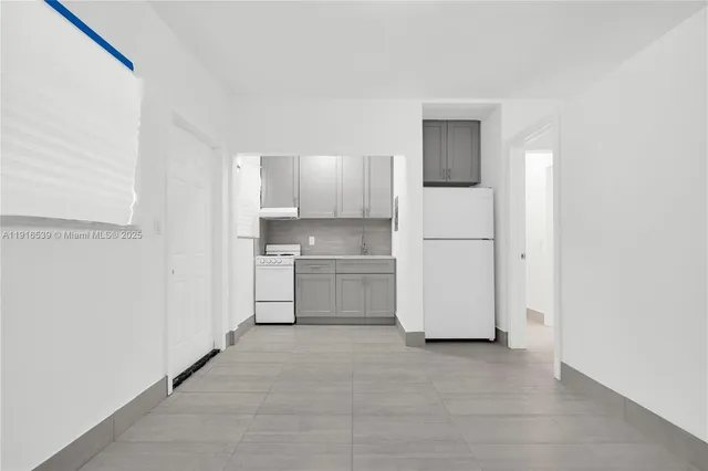 a view of a kitchen with a sink and dishwasher a refrigerator with white cabinets