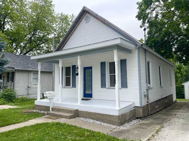 a view of a white house with a yard and large tree
