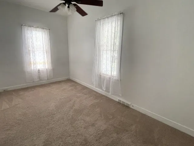 an empty room with windows and a ceiling fan