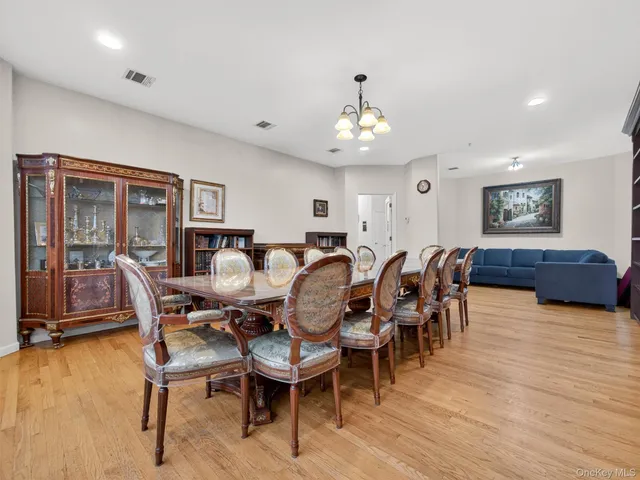 a view of dining room and livingroom with furniture wooden floor a rug a painting and a chandelier